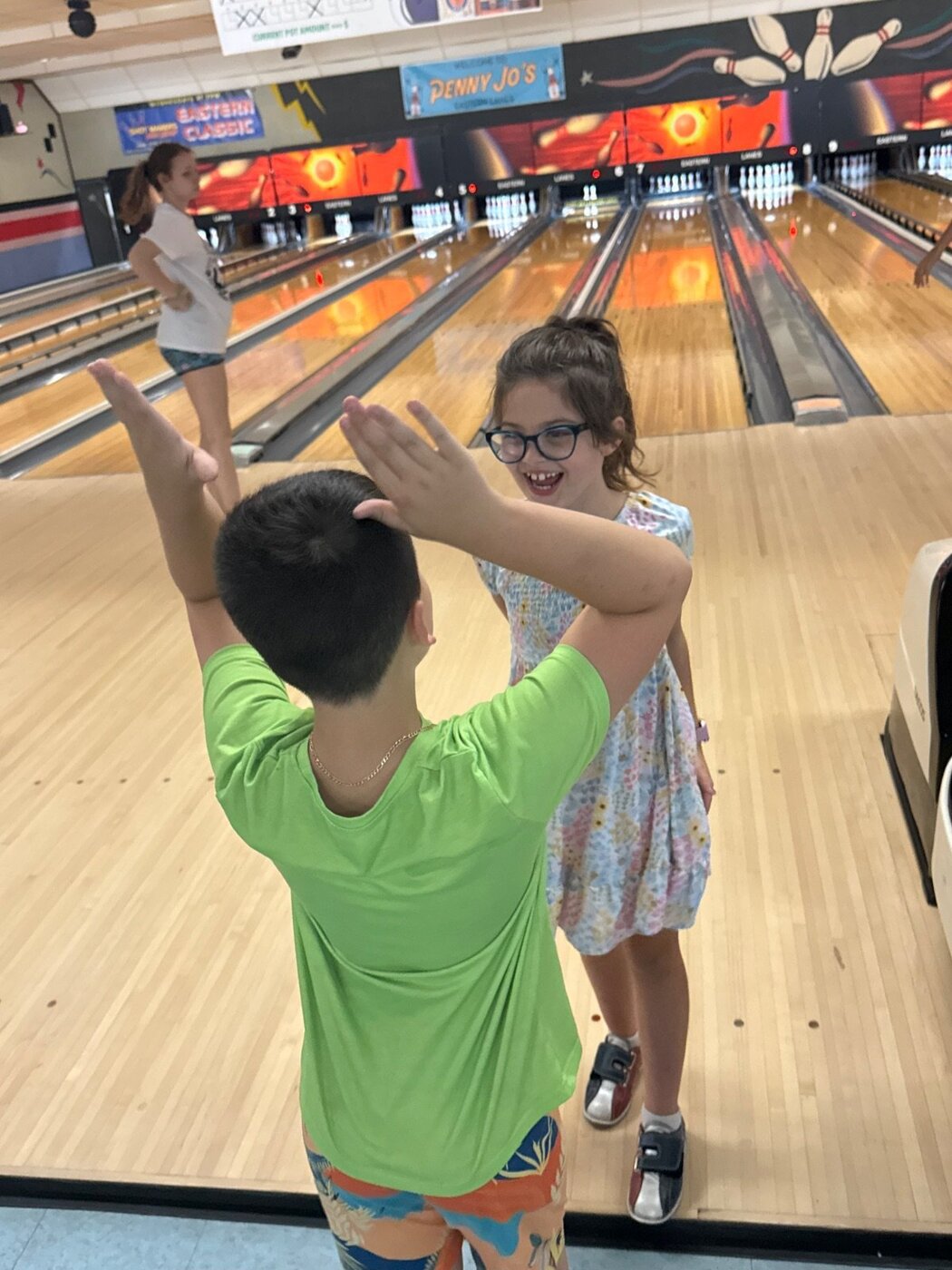 Kids high-fiving by the bowling lanes